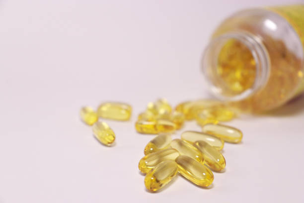 istock fish oil capsules with omega 3, blurred bottle in background 1392867624