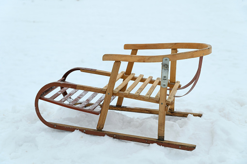 Antique wooden sleds with metal inserts and bindings. The sleds are on clean snow.