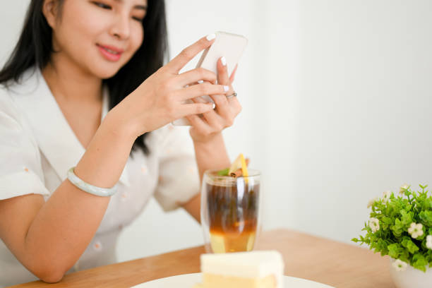istock Attractive Asian woman relaxes in cafe, using her smartphone 1392876001