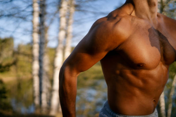 Close-up shot of unrecognizable young athletic man jogging in nature by the lake on sunny day