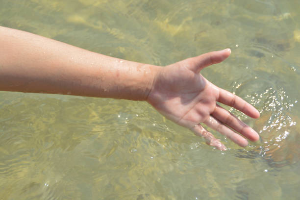 istock Someone hand play the water in the sea. 1392882207