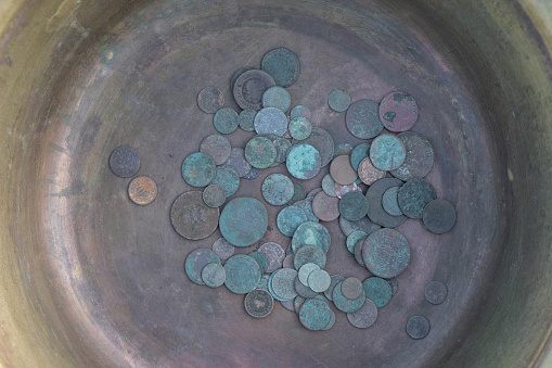 Ancient copper coins in a copper bowl. Copy space.