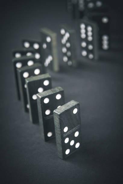 istock Black dominoes chain on dark table background 1392887356