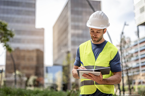 A civil engineer works on arranging parks around residential buildings, he controls the works via his tablet device