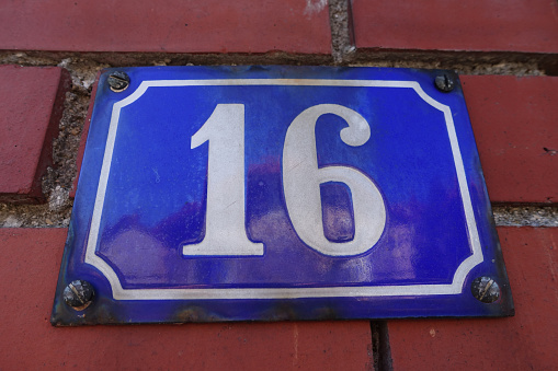 Home address numeration  Plate numbered 16 fixed on a brick wall  Paris region