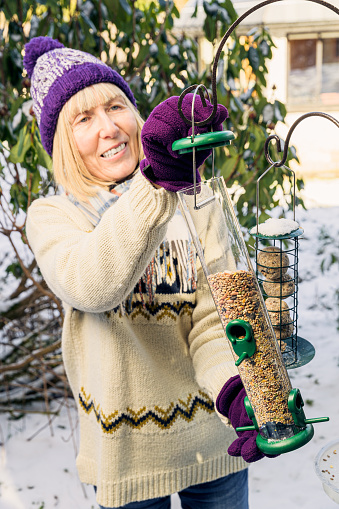 Woman refilling her bird feeder during winter.