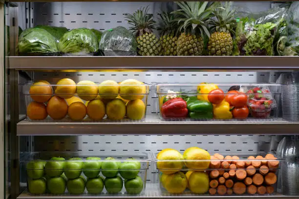 Multi coloured Organic Fresh Vegetables and Fruit presented on cold shelves in plastic containers ready to be sold