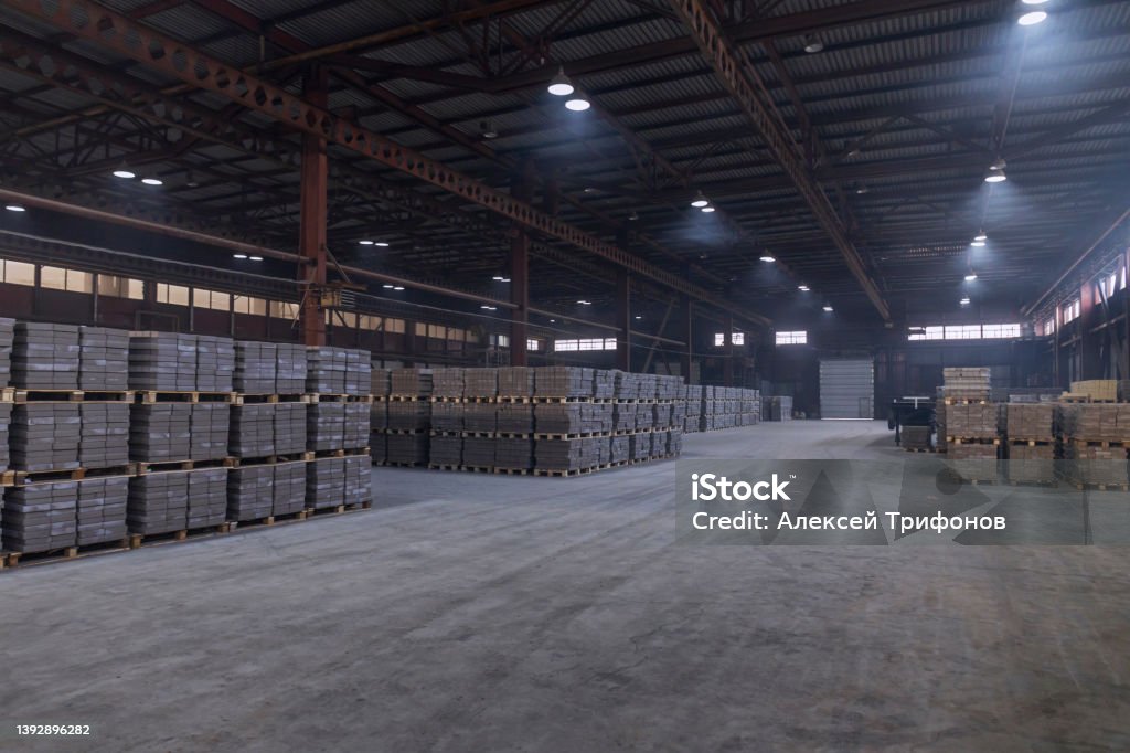 Warehouse of finished products at the enterprise for the production of bricks for construction. Warehouse of finished products at the enterprise for the production of bricks for construction. Industrial workshop with concrete floor and artificial lighting. Warehouse Stock Photo