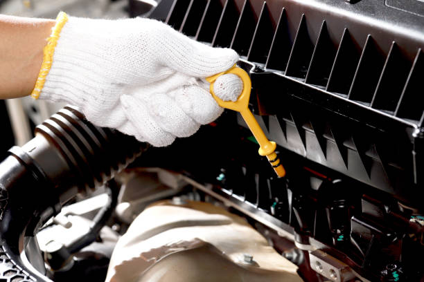 Car mechanic checking engine oil before leaving stock photo