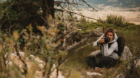 Checa, Spain - July 7, 2014: A woman photographer with a Nikon camera takes pictures in the forest.