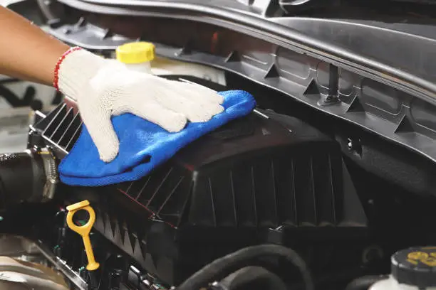 Photo of cloth worker cleaning the car engine room