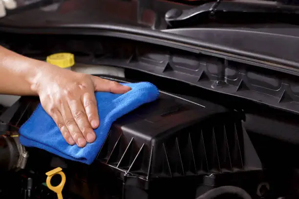 Photo of cloth worker cleaning the car engine room