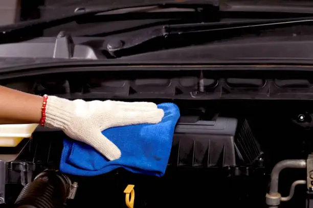 Photo of cloth worker cleaning the car engine room