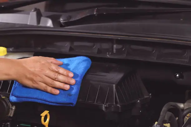 Photo of cloth worker cleaning the car engine room