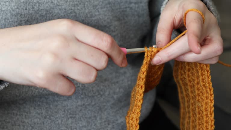 Young woman crocheting with yellow wool