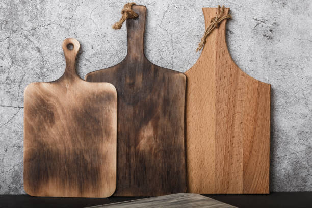 istock Samples of various rustic wooden cutting boards on a kitchen countertop against a concrete wall. Production of household goods 1392906966