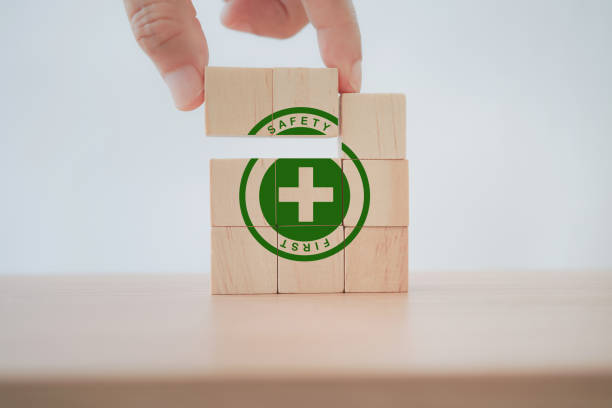 senior's hand completed green safety first sign on wooden cube blocks with copy space, work safety, caution work hazards, danger surveillance, zero accident concept. Safety banner stock photo