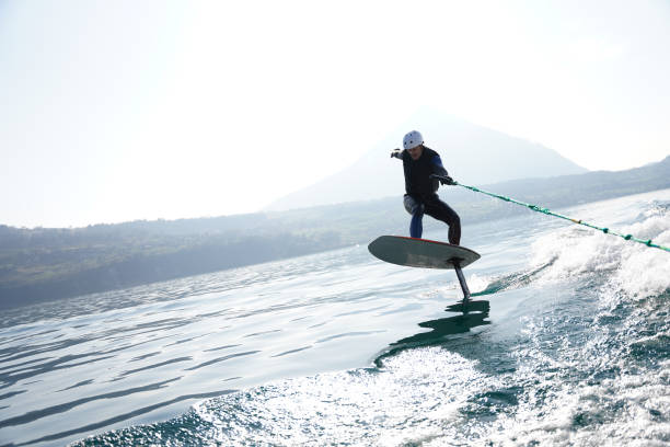 vista dell'uomo che cavalca la scia dietro la barca a motore - wakeboarding surfing men vacations foto e immagini stock