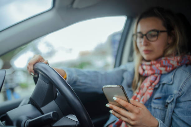 While waiting for the car in front of her to move forward, the woman uses a mobile phone. stock photo