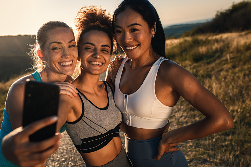 Portrait of three sporty young woman making selfie after running outdoors.