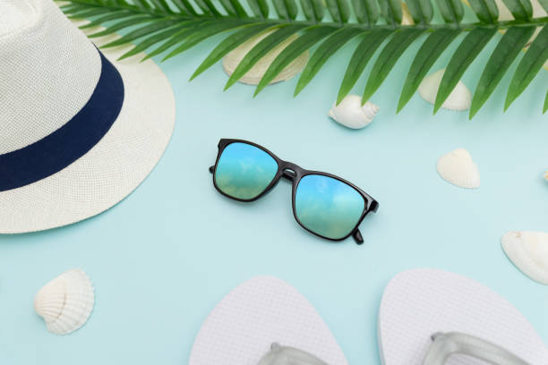 istock Summer beach accessories on blue background. Hat, glasses, slippers, shells and palm leaves 1392912068