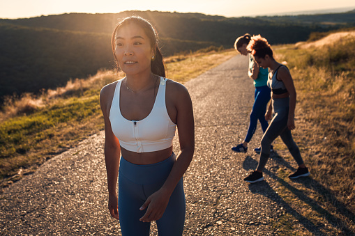 Portrait of young woman preparing for running with her friends outdoors.