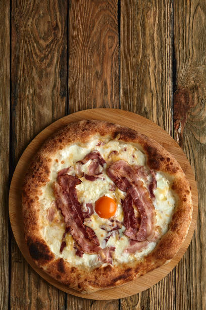 istock Carbonara pizza with bacon and egg on wooden background 1392914459