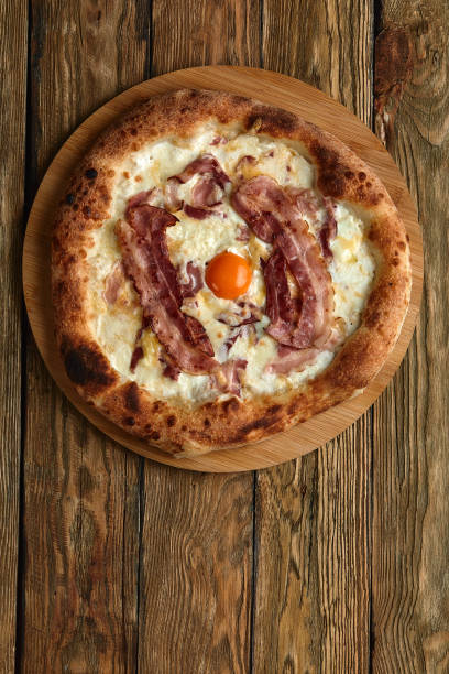 istock Carbonara pizza with bacon and egg on wooden background 1392914469