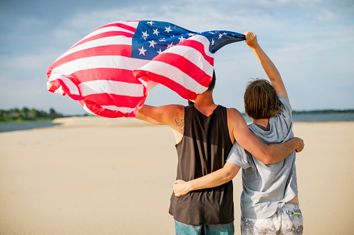 Couple with American flag at the beach celebrating Independence Day