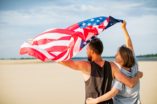 Couple with American flag at the beach celebrating Independence Day