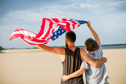 Couple with American flag at the beach celebrating Independence Day