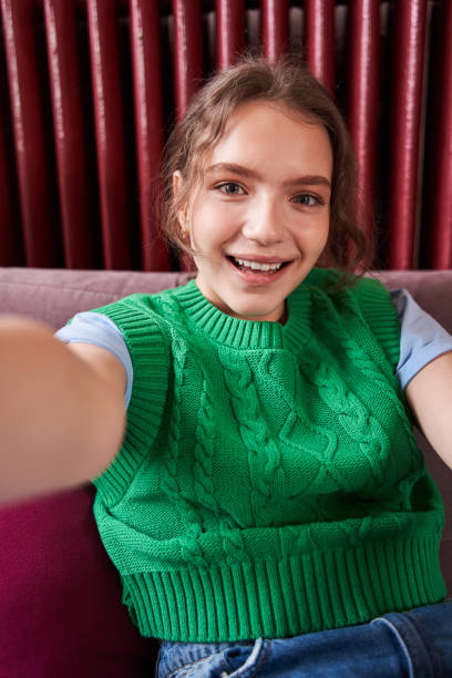 Teen girl looking at the smartphone screen with pleasure smile while having video call stock photo