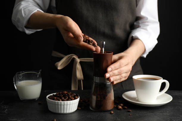 donna che usa il macinino da caffè manuale al tavolo nero, primo piano - coffee coffee bean coffee grinder cup foto e immagini stock