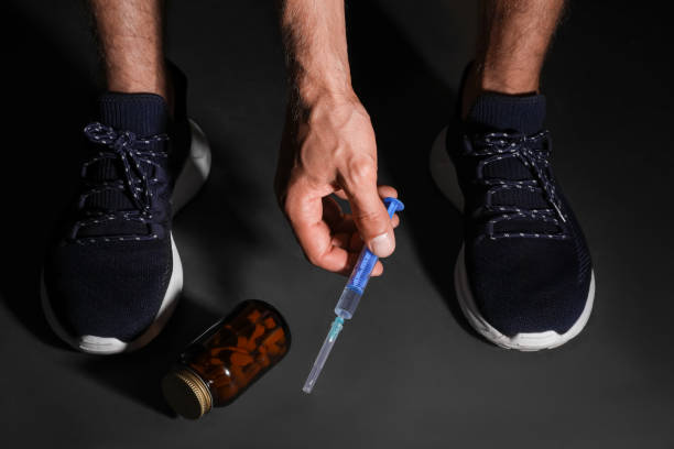 homme prenant une seringue sur un sol noir, gros plan. concept de dopage - steroids photos et images de collection
