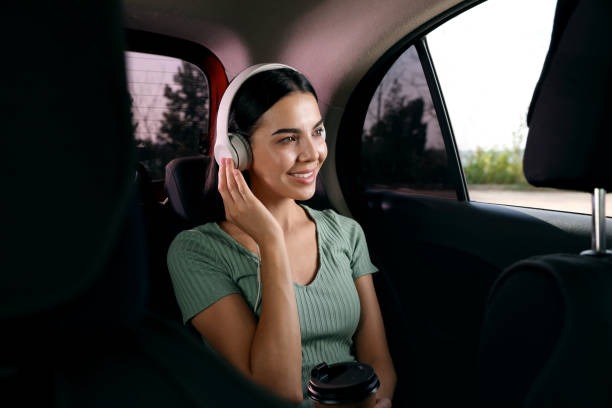 現代のタクシーで音楽を聴く若い女性 - personal land vehicle audio ストックフォトと画像