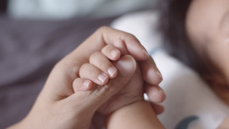 Mother holding hand of newborn baby