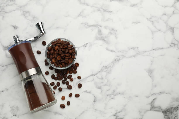 istock Manual coffee grinder with powder and beans on white marble table, flat lay. Space for text 1392919939
