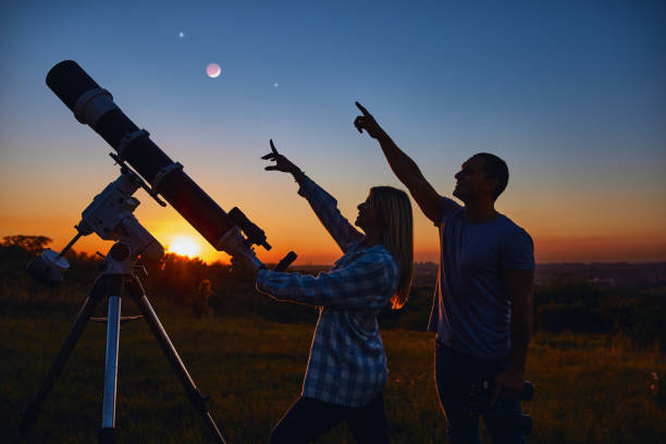 istock Couple stargazing together with a astronomical telescope. 1392922435