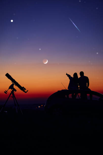istock Couple stargazing together with a astronomical telescope. 1392922475
