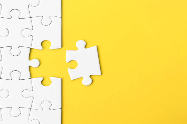 White jigsaw puzzle on yellow background with copy space stock photo