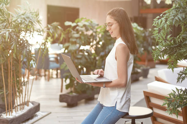 istock smiling woman with a laptop standing in an empty cafe hall 1392930379