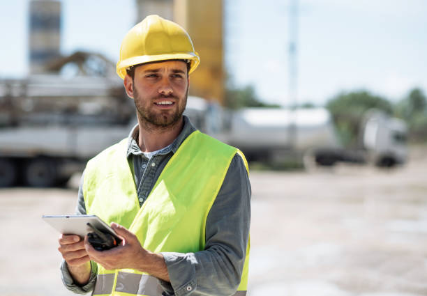 istock Portrait of industry worker - engineer with helmet on construction site using walkie talkie to talk to other employees 1392930381