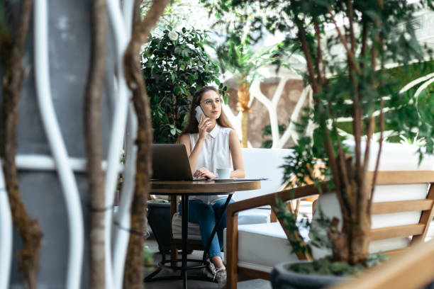 istock visitor of a cozy Internet cafe talking on a smartphone 1392930585