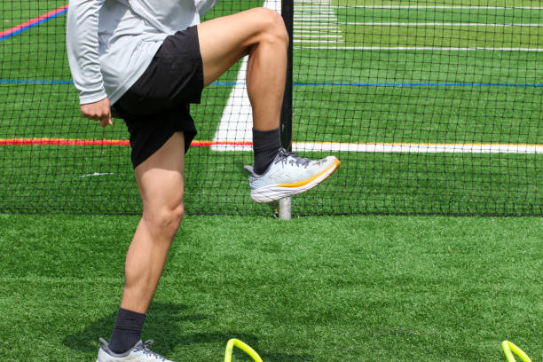 istock Athlete standing over small yellow hurdles on a green turf field 1392937863