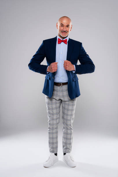 istock Man wearing bow tie and checked pants while standing at isolated grey background 1392942418