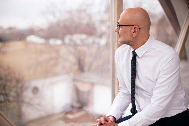 istock Thinking businessman portrait while standing at the window 1392943693