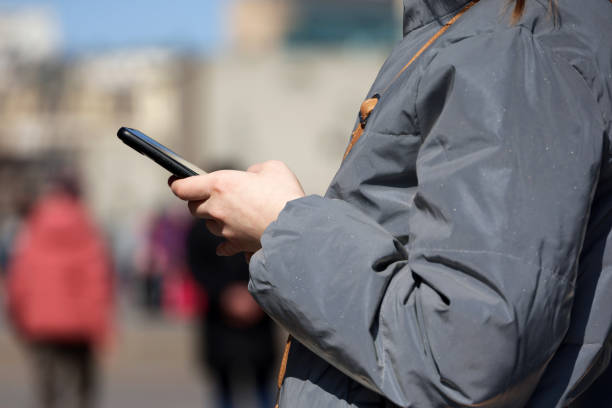 istock Female hands with smartphone close up on blurred people background 1392945796