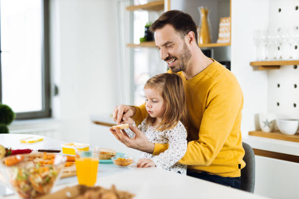 Happy father and daughter making breakfast in the kitchen