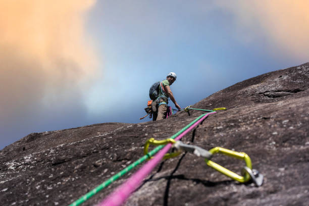 Climber on the rocky wall climbing up with rope