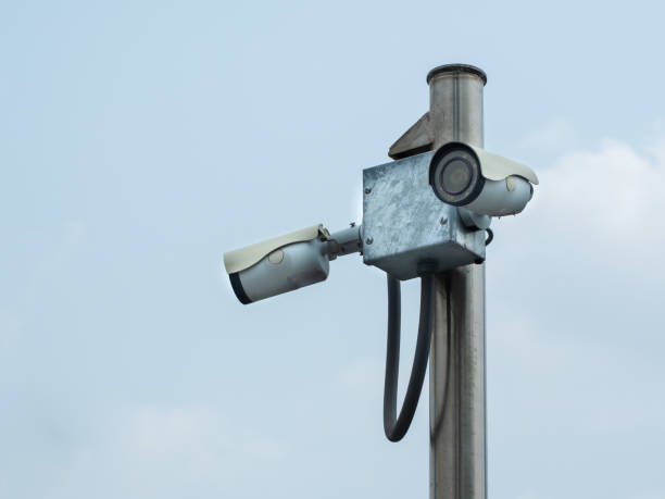 istock Old pair of surveillance camera or CCTV installed on poles 1392961415